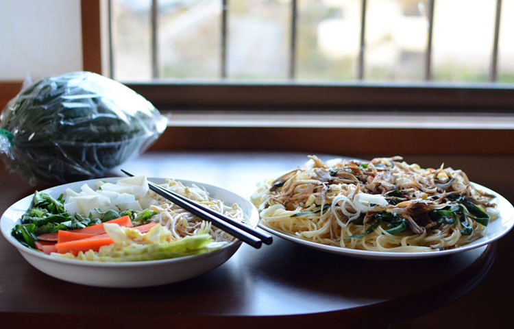 Home-cooked meal of noodles and mushrooms, fried bean sprouts, and vegetables.